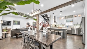 Een moderne keuken met een centraal eiland, houten vloeren en een trap naar een hoger niveau.
