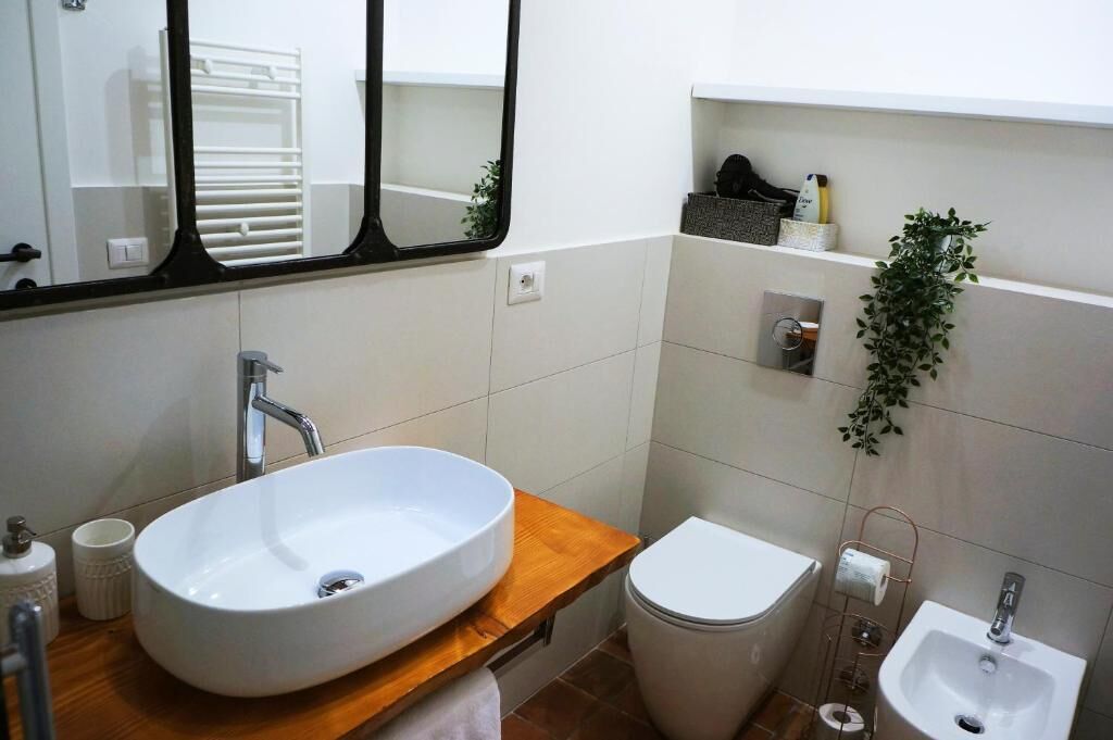 A modern bathroom with a large oval sink, a toilet, and a bidet.