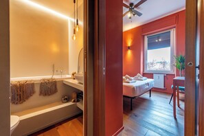 A modern bathroom with a bathtub, towel rack, and a window with a view. - Residenza Pasolini - Two Bedroom Apartment, Sleeps 6 (Rome)