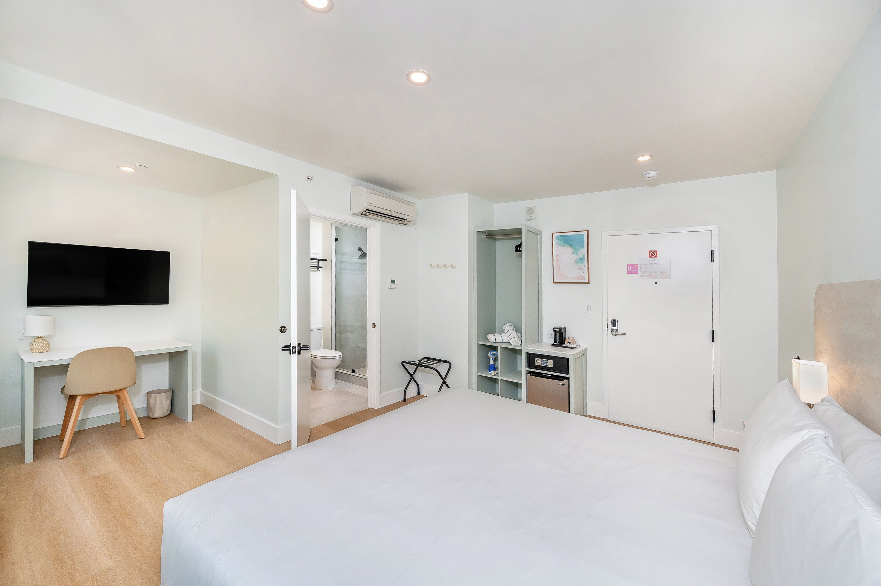 Une chambre d’hôtel comprenant un lit, un bureau, une télévision, une armoire et une salle de bain.
