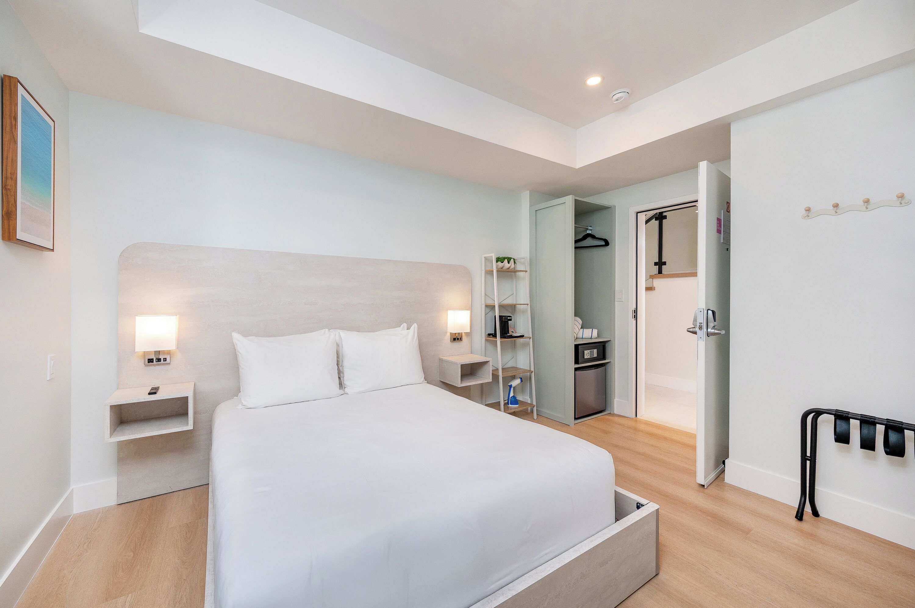 A modern hotel room with a large bed, bedside tables, a wardrobe, and a bathroom.