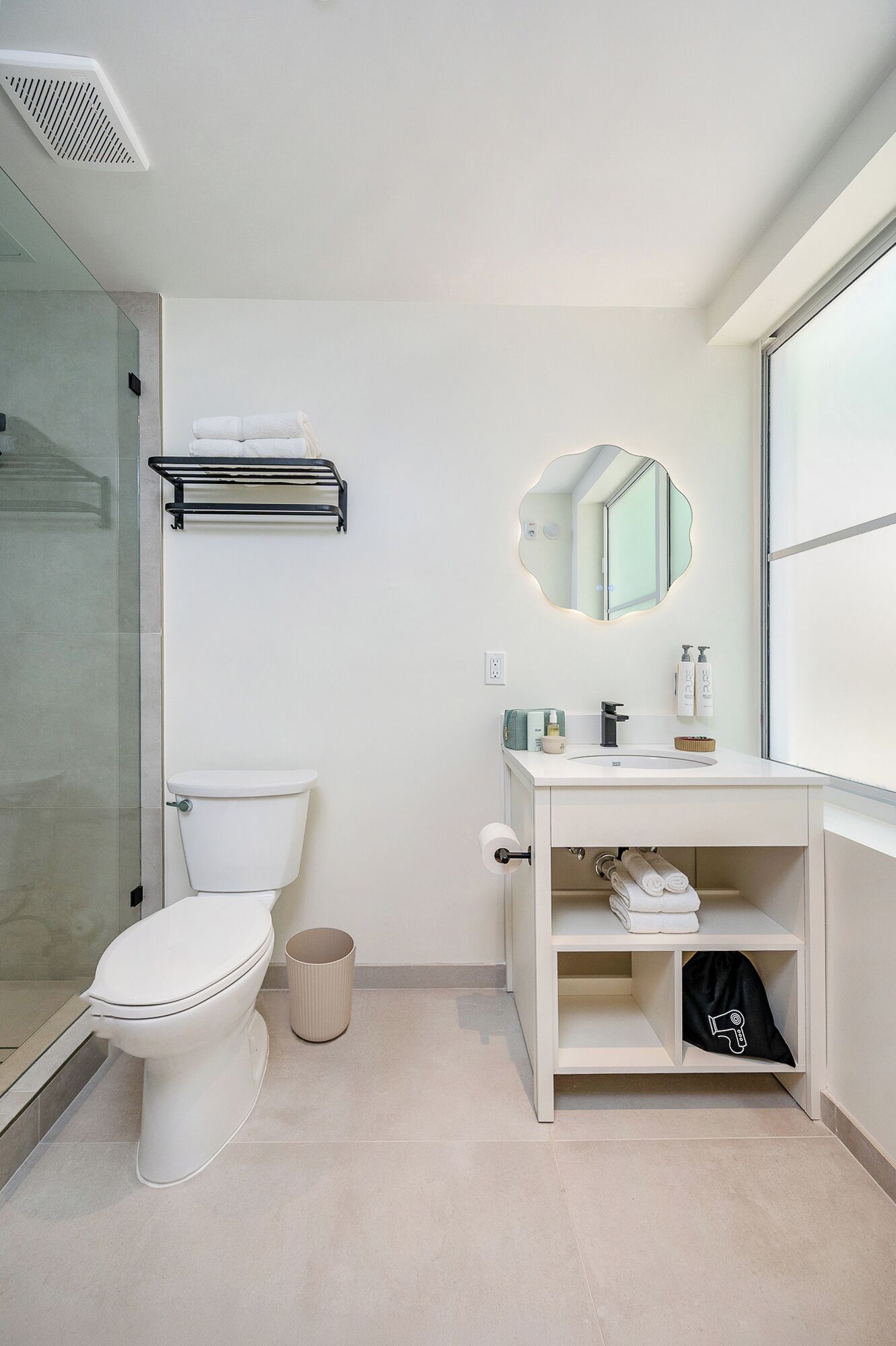 A modern bathroom with a toilet, a sink, a mirror, and a shower area.