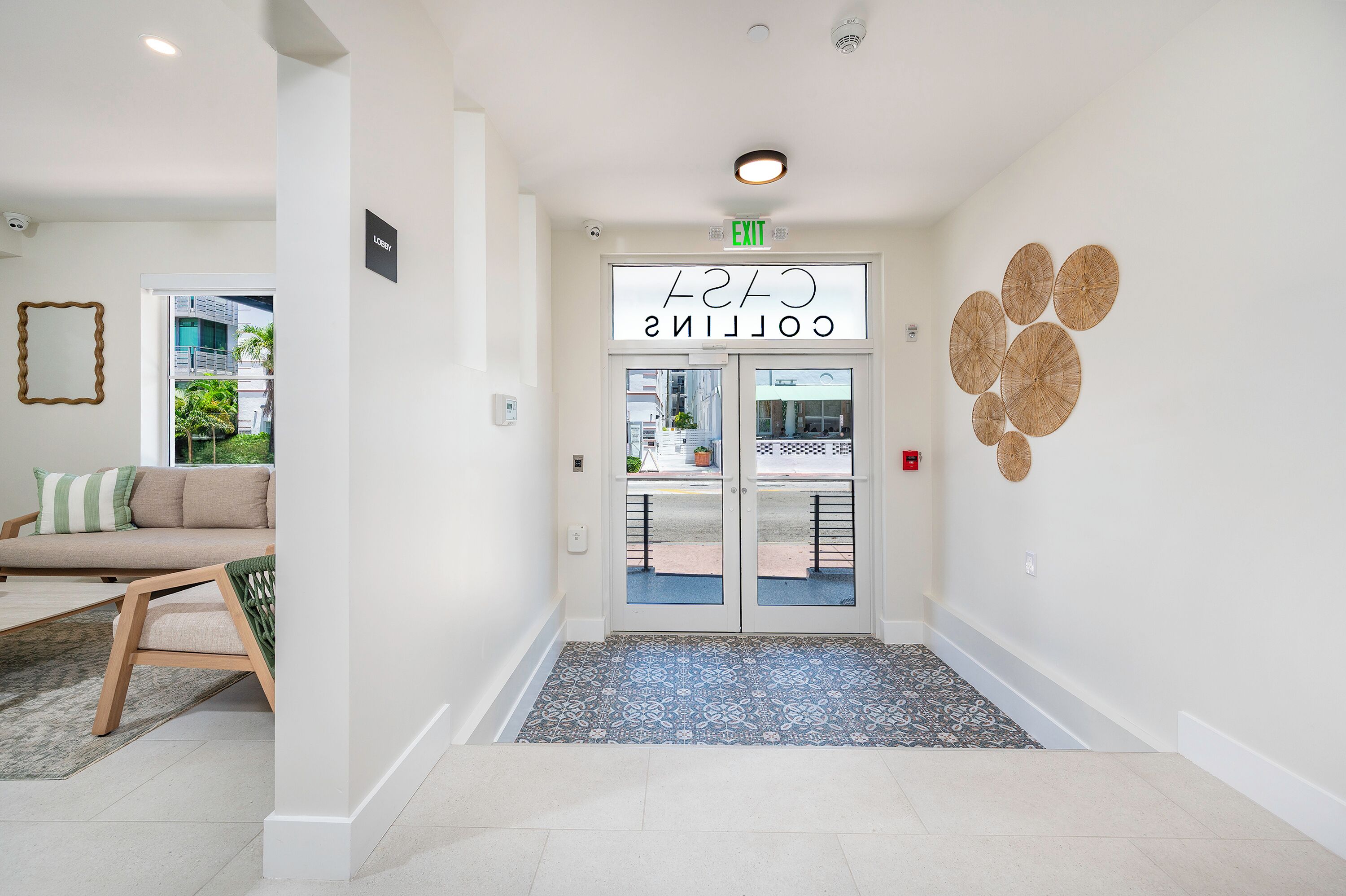 L’entrée d’un hôtel, avec une enseigne indiquant « City Collection », un comptoir d’accueil et un tapis à motifs.