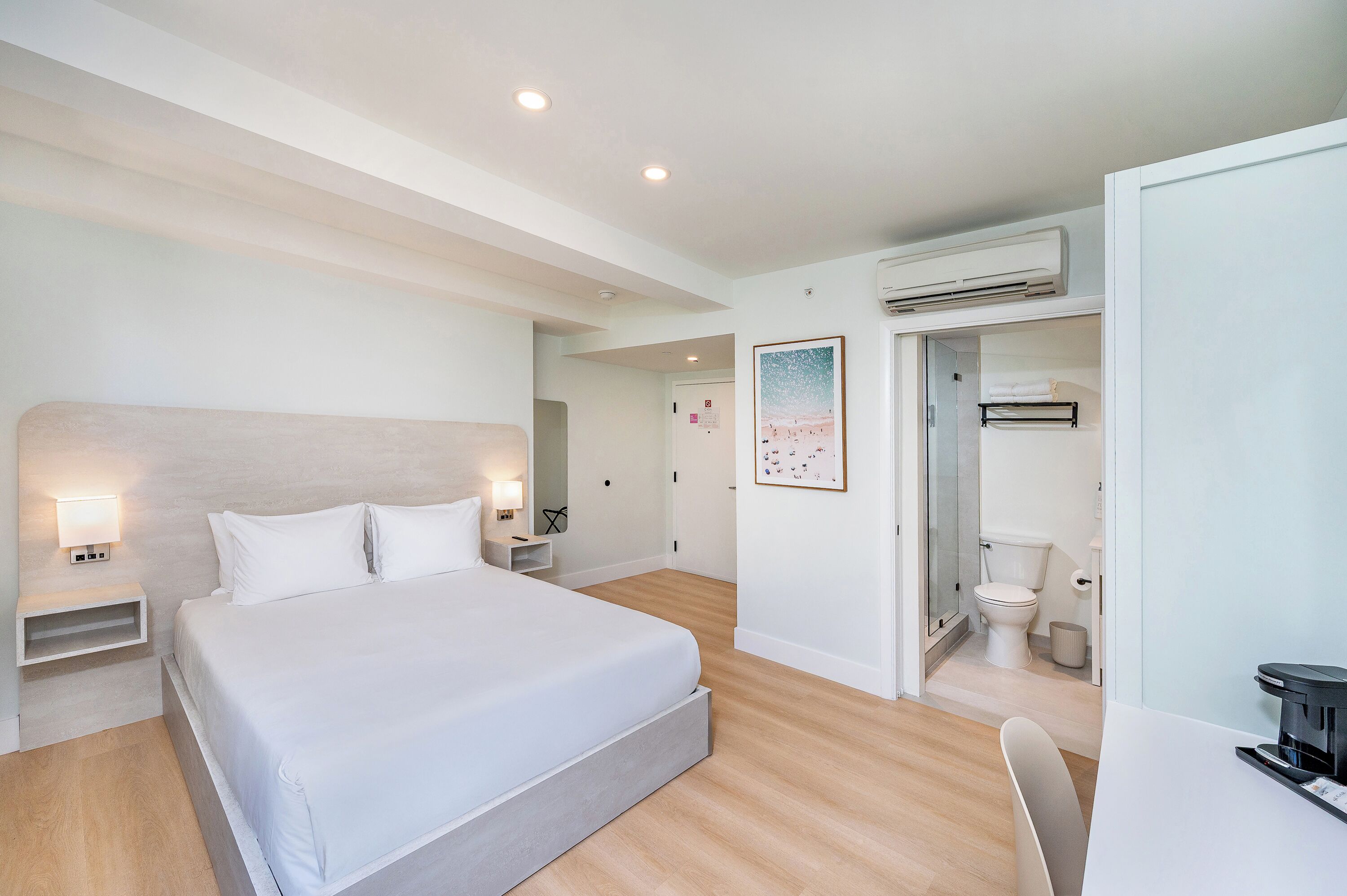 A modern hotel room with a large bed, bedside tables, a desk, and a bathroom.