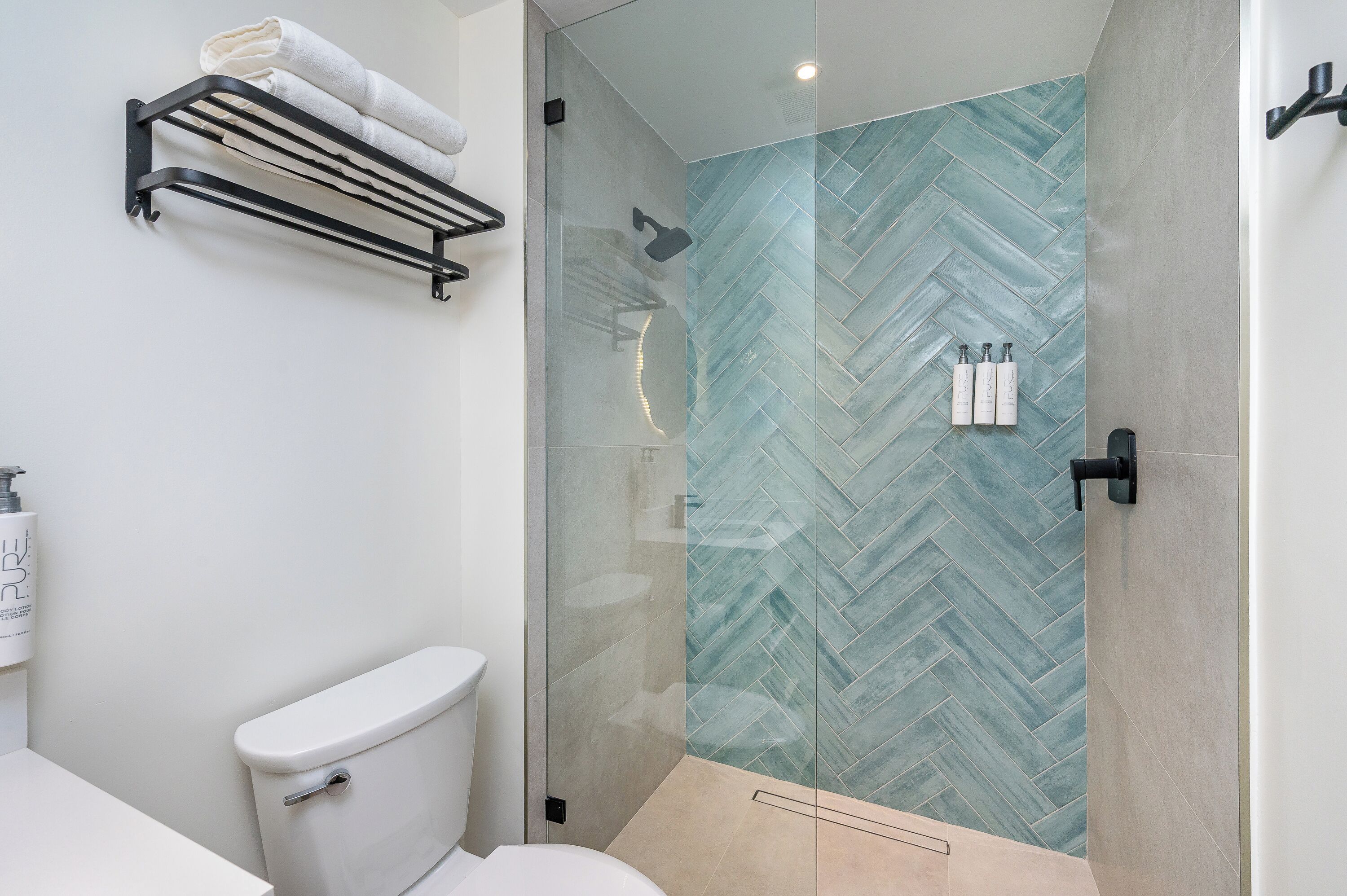 Un baño moderno con cabina de ducha de vidrio, un inodoro y un perchero para toallas.