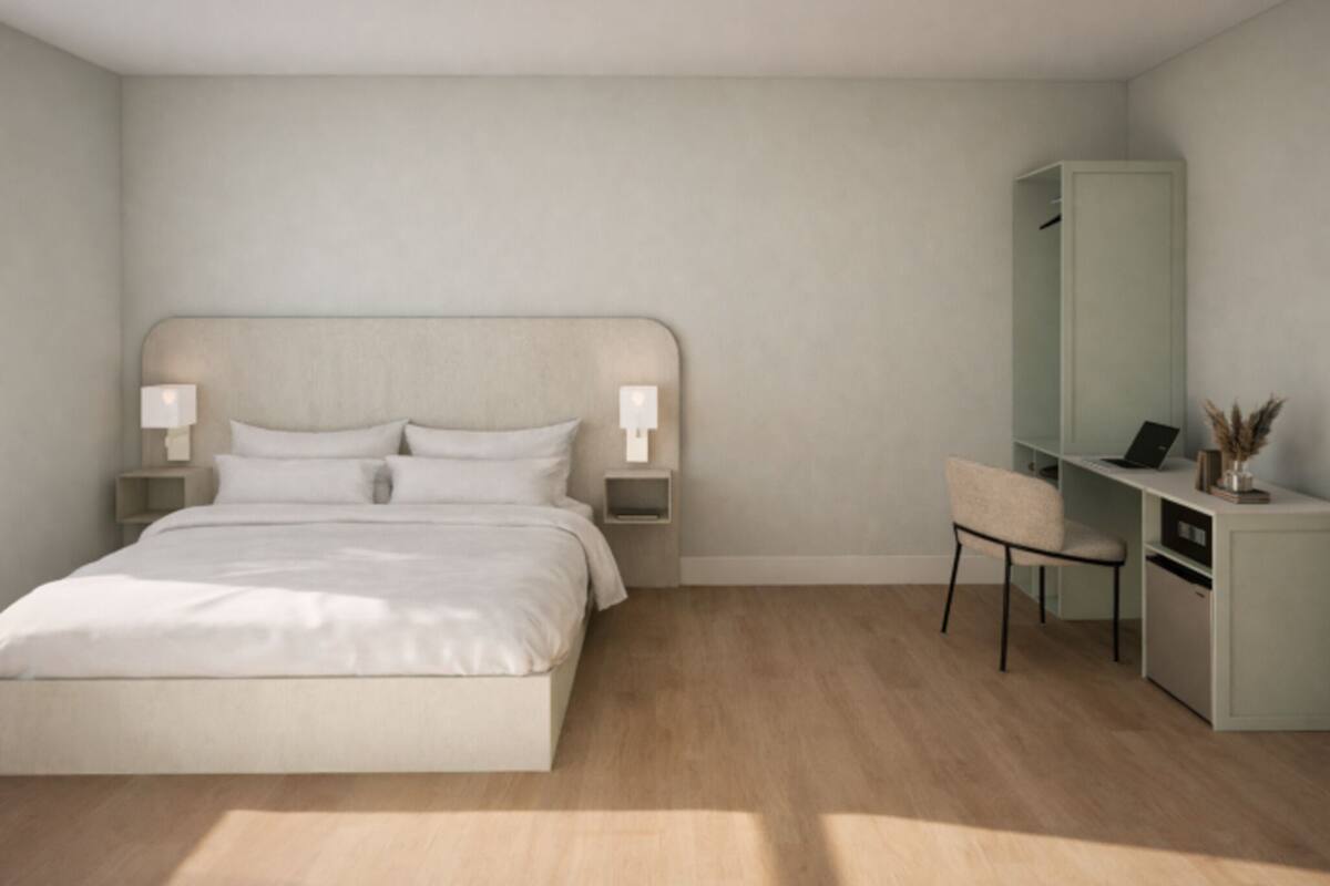 Un dormitorio con cama, lámparas de noche, un escritorio y una silla.