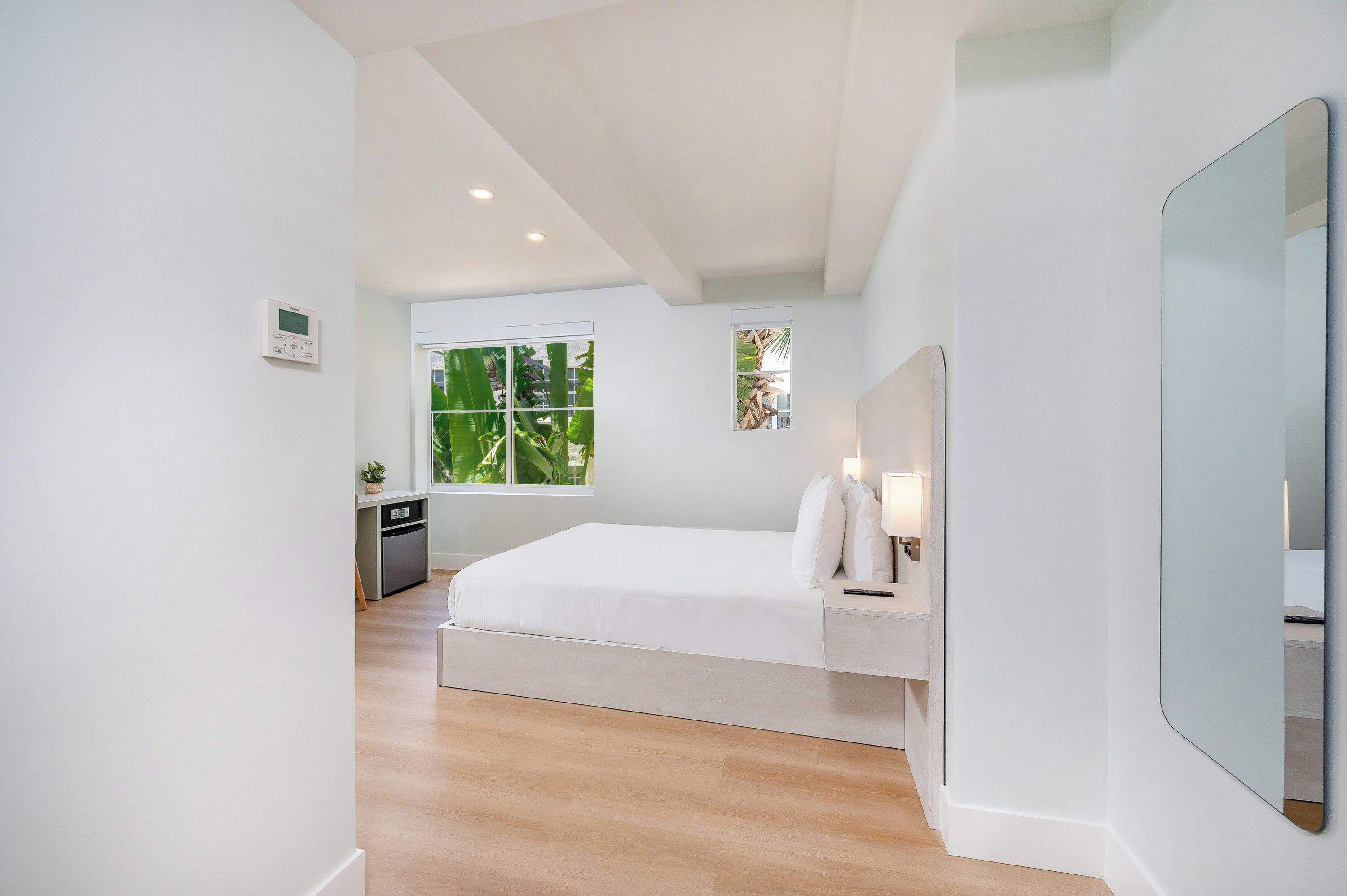 Un dormitorio moderno con una cama, mesita de noche y un espejo grande.