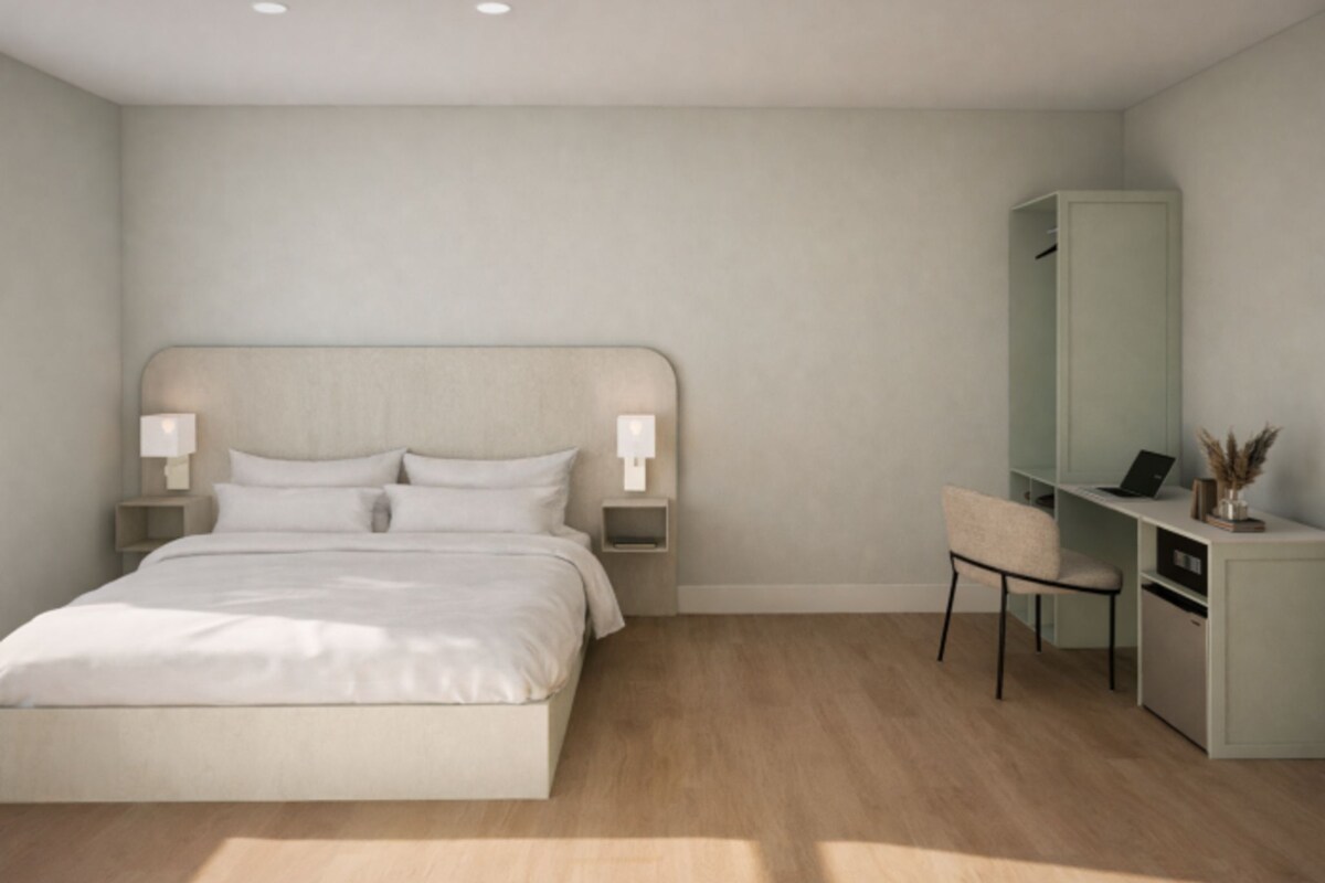 A bedroom with a bed, bedside lamps, a desk, and a chair.