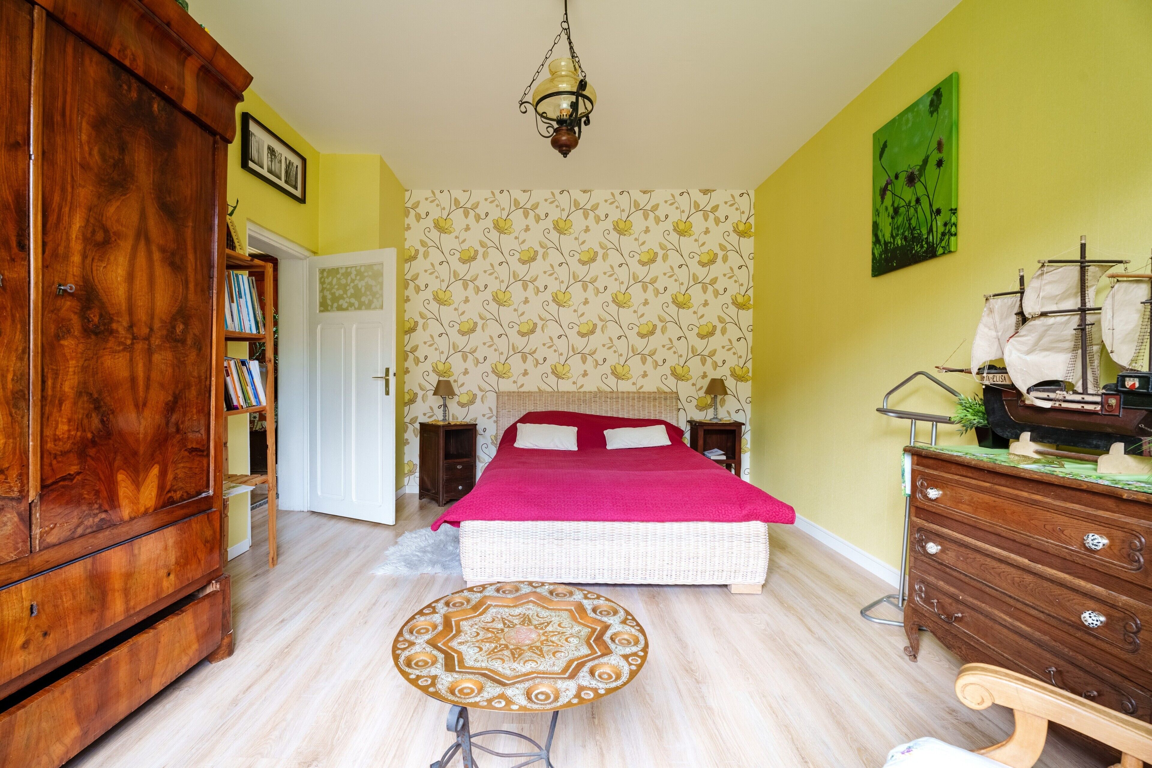 Een slaapkamer met een bed, een houten garderobe en een ronde tafel.