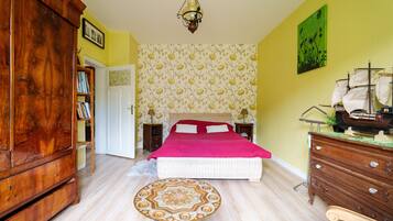 Een slaapkamer met een bed, een houten garderobe en een ronde tafel.