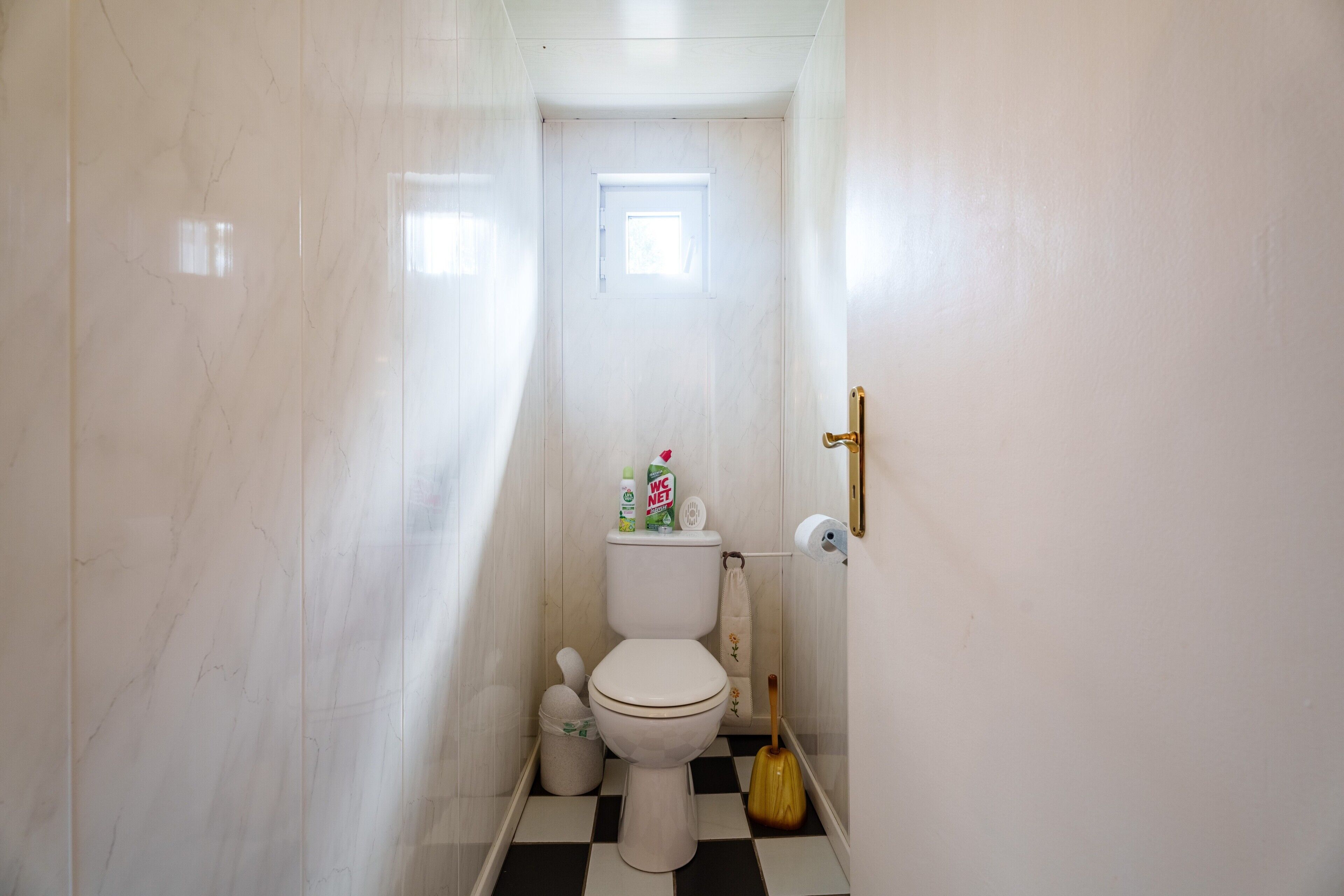Une petite salle de bain étroite, équipée de toilettes, d’un bidet et d’un porte-rouleau de papier toilette.