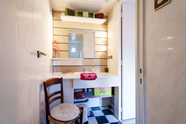 A bathroom with a white sink, a mirror, a wooden chair, and a checkered floor.