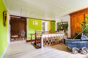 Une pièce avec un plancher en bois, un mur vert, une porte en bois et un chariot bleu.
