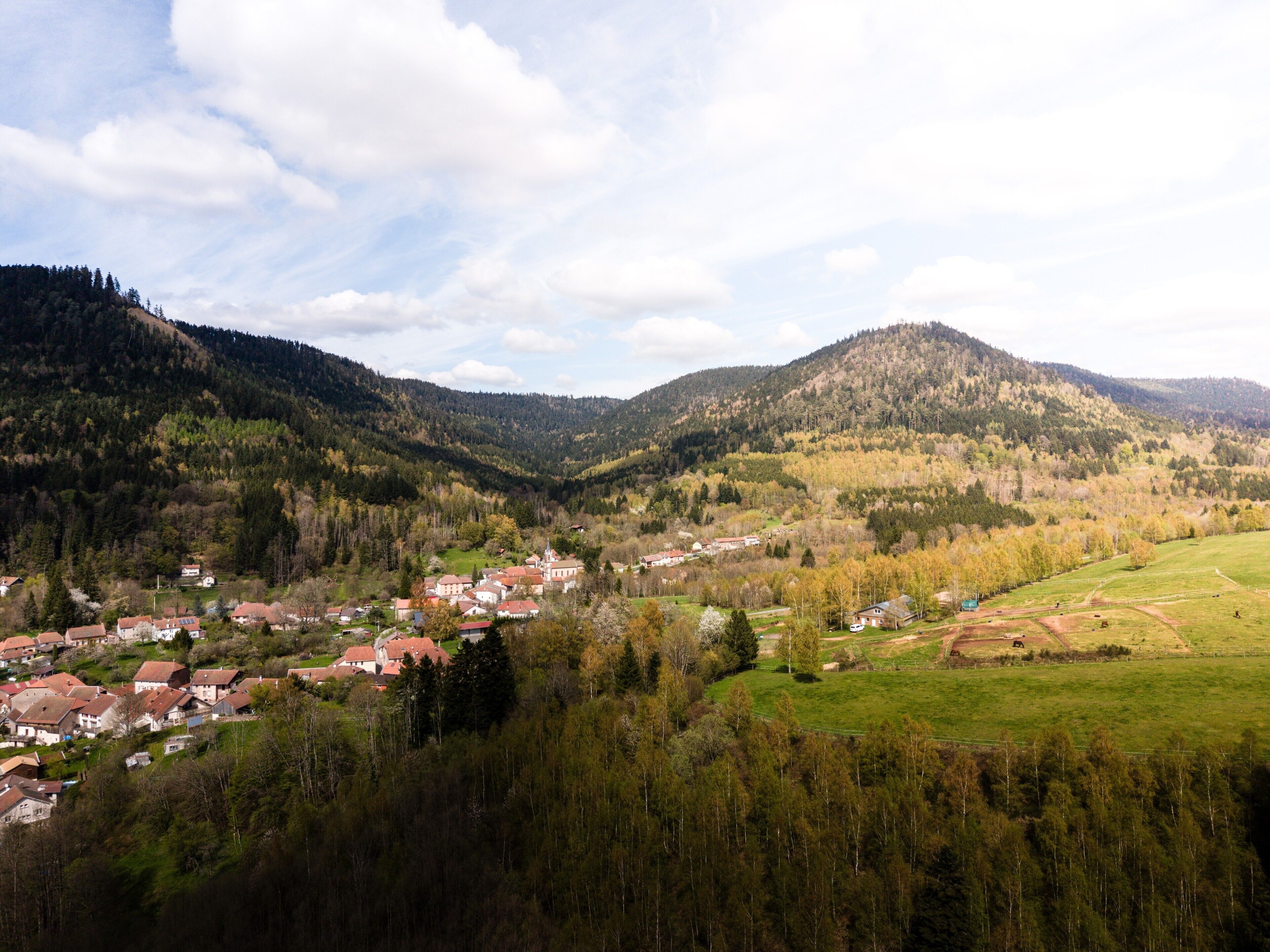 Un valle con un pueblo pequeño, rodeado de colinas y árboles.