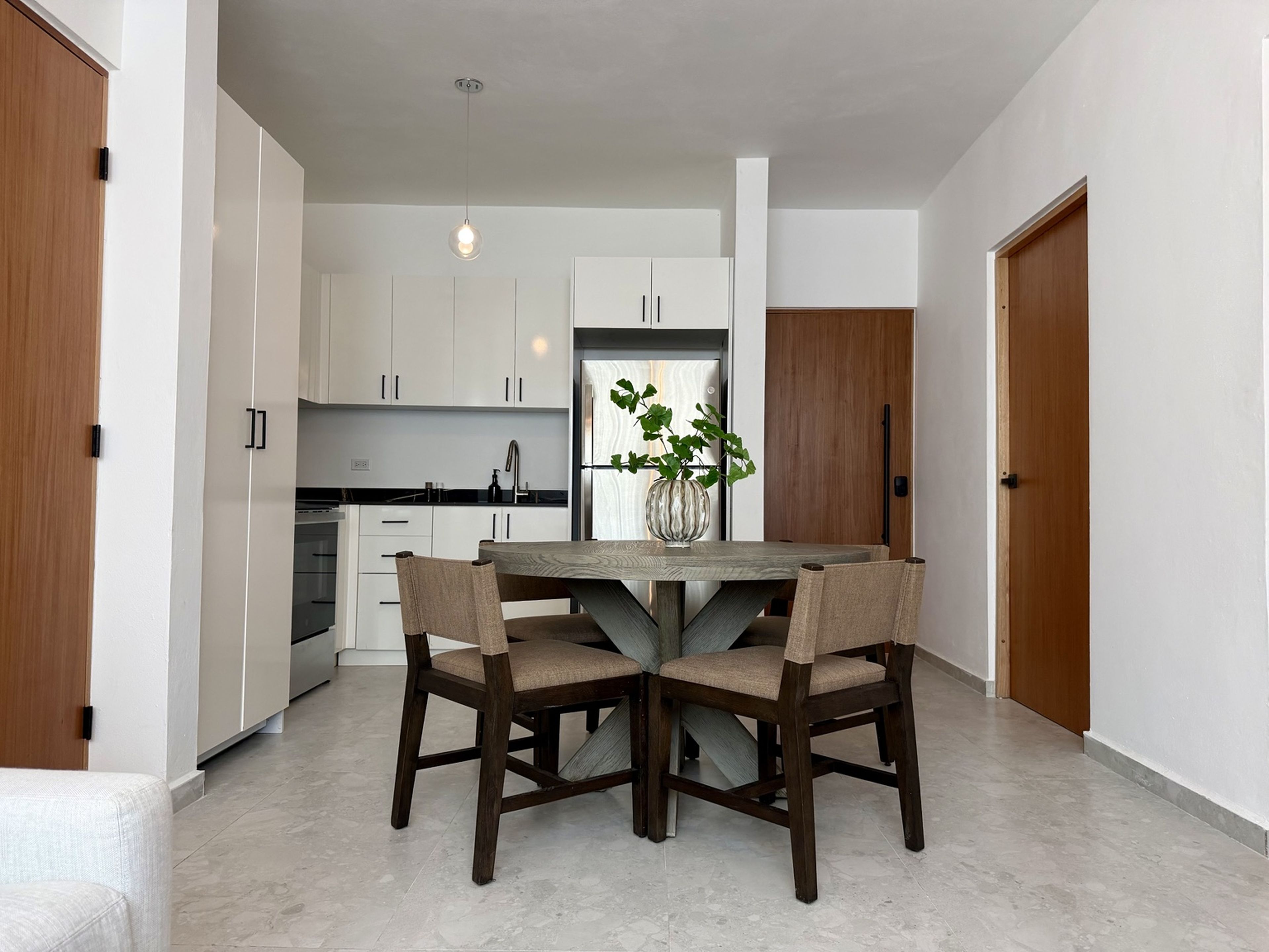 A modern kitchen with white cabinets, a central island, and a dining area with two chairs.