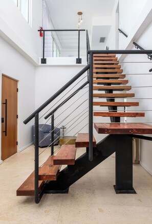 A modern staircase with wooden steps and black railings, leading to an upper floor. - Ashford Apartments (San Juan)