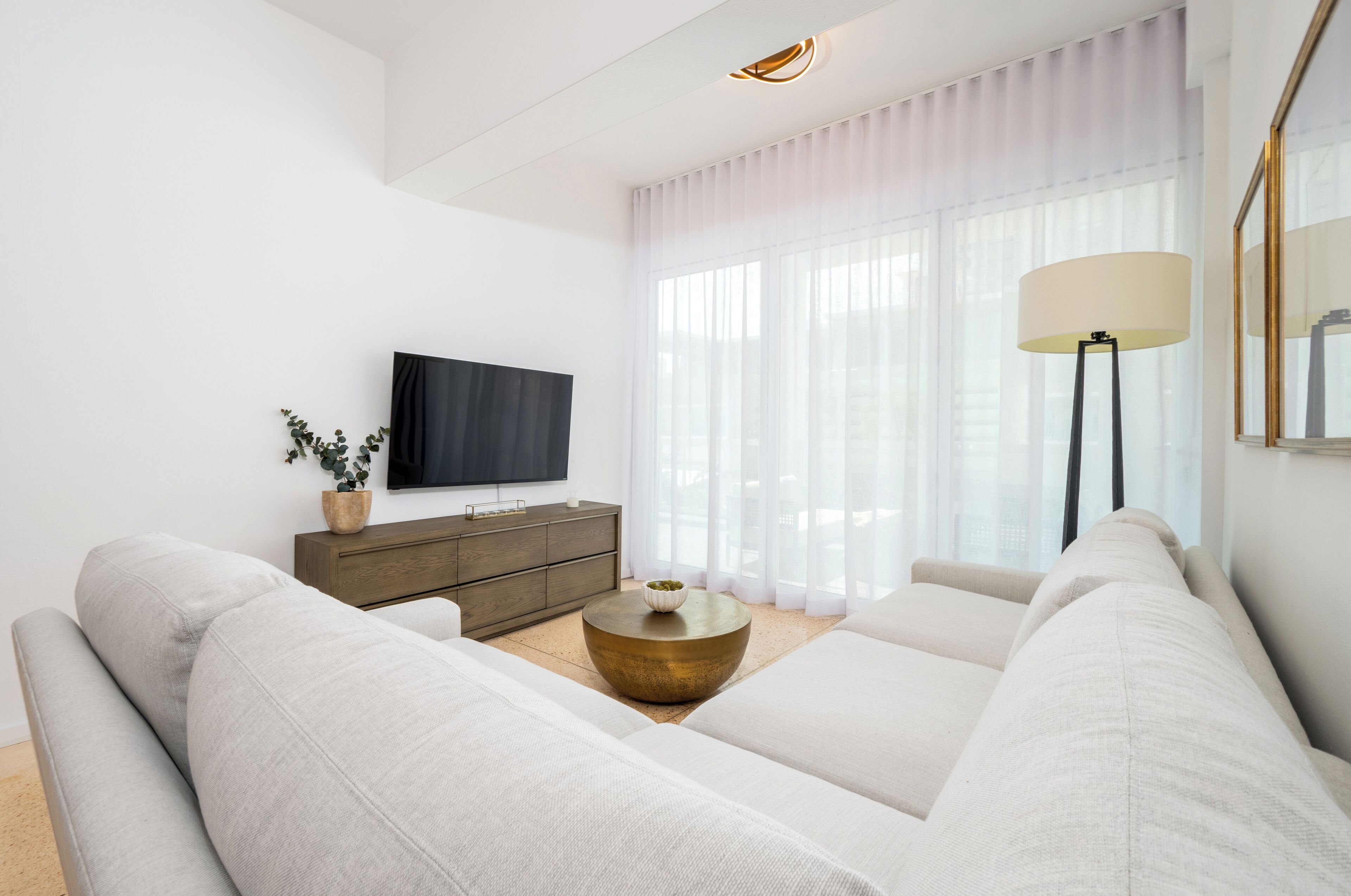 A modern living room with a large sofa, a coffee table, a TV, and a lamp.