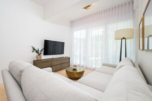 Una sala de estar moderna con un sofá grande, una mesa de centro, un televisor y una lámpara.