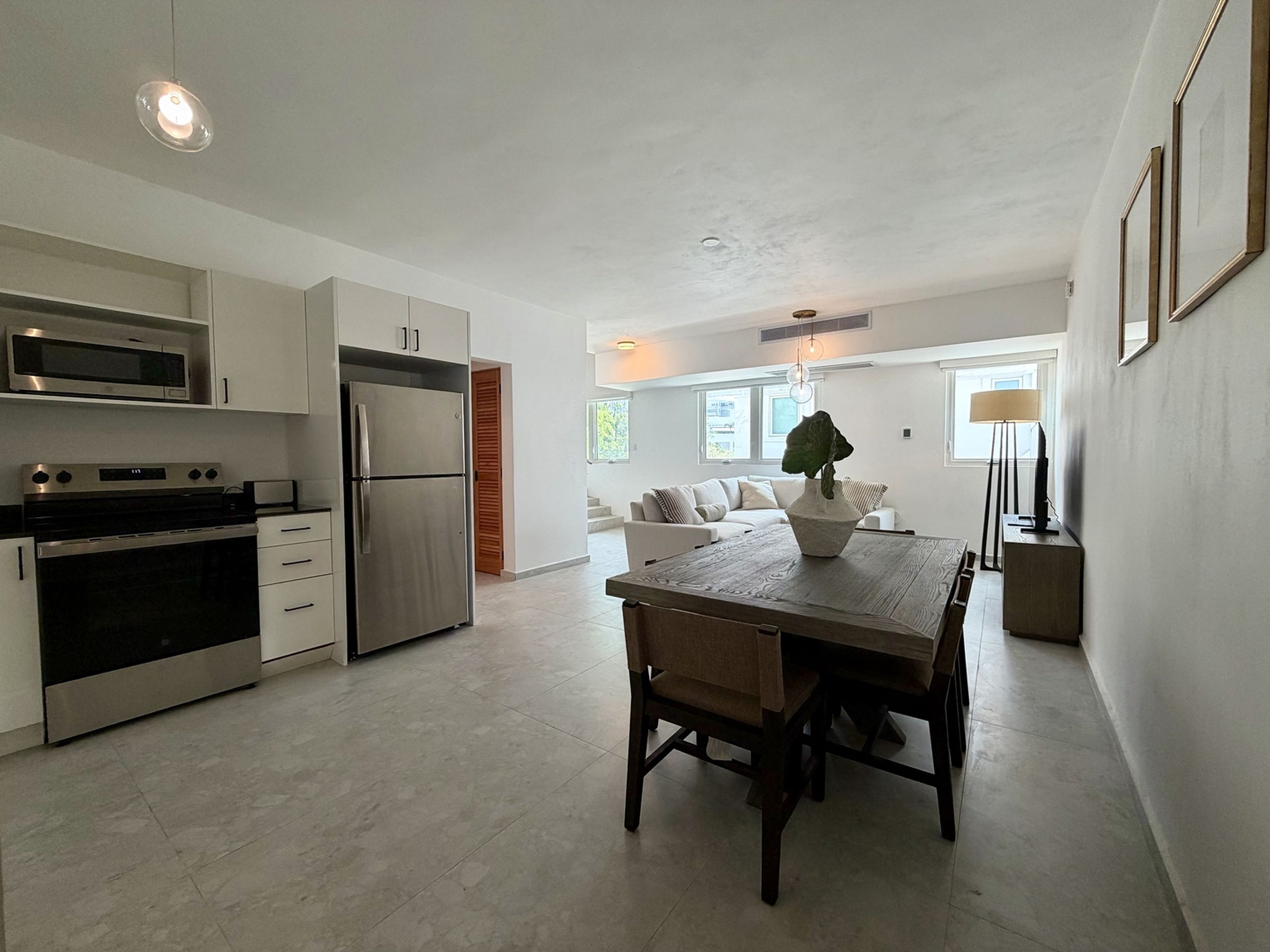 A modern kitchen with a dining area, stainless steel appliances, and a large window.