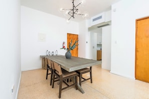 A dining area with a wooden table, chairs, a vase with flowers, and a modern chandelier. - Ashford Apartments (San Juan)
