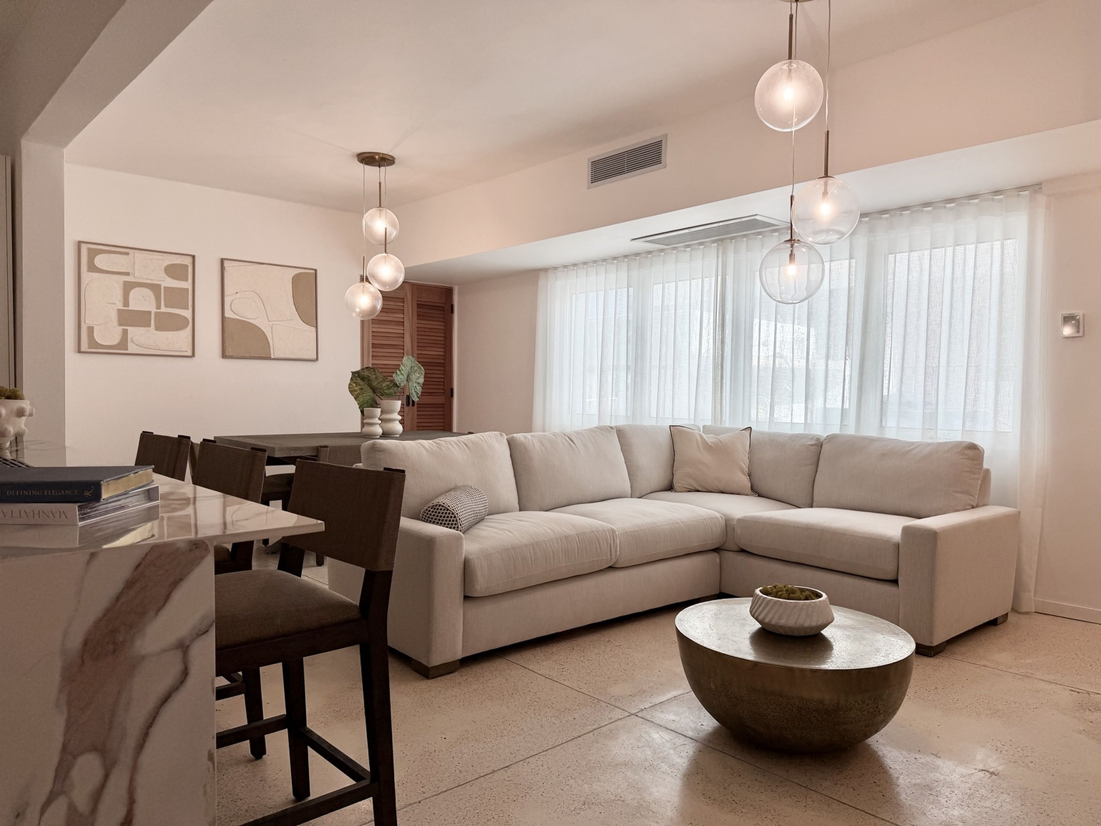 Una sala de estar moderna con un sofá modular, una mesa de comedor con sillas y una mesa de centro.