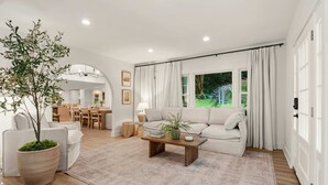 A modern living room with a sofa, coffee table, and a large potted plant. - 7 BDR Retreat w Guest Houses Waterfall Trail (Hendersonville)