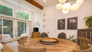 Un coin repas avec une table ronde en bois, des chaises et un téléviseur posé sur un meuble.