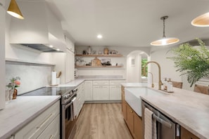 A modern kitchen with white cabinets, a central island, and pendant lighting. - 5BR Estate w Guesthouse Private Waterfall Trail (Hendersonville)