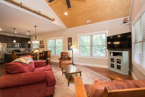 A spacious living room with a red sofa, wooden coffee table, and a television. - 3BR Retreat Ensuite Baths Fire Pit (Arden)