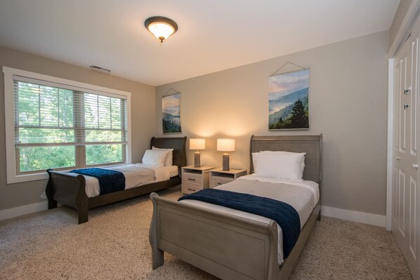 A bedroom with two beds, a window, and a ceiling light. - 3BR Retreat Ensuite Baths Fire Pit (Arden)