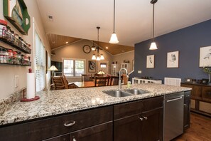 A kitchen with granite countertops, a dishwasher, and a dining area with wooden chairs and a table. - 3BR Retreat Ensuite Baths Fire Pit (Arden)