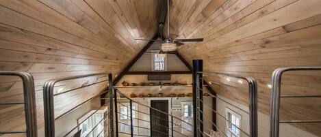 A wooden interior with a staircase, metal railings, and a ceiling fan.