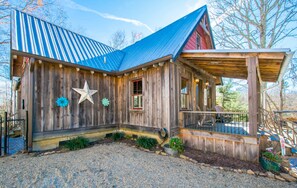 A wooden cabin with a sloped metal roof, a covered porch, and a gravel driveway. - Rustic-chic 2BR Cabin w Clawfoot Tub Near Trails (Hendersonville)