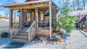 A rustic wooden building with a porch, steps, and a small tree. - Rustic-chic 2BR Cabin w Clawfoot Tub Near Trails (Hendersonville)