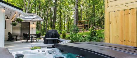 A backyard with a hot tub, patio furniture, and a wooden deck.
