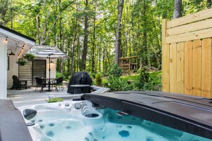 A backyard with a hot tub, patio furniture, and a wooden deck.