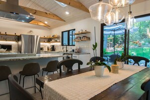 A modern kitchen with a central island, wooden beams, and pendant lighting.