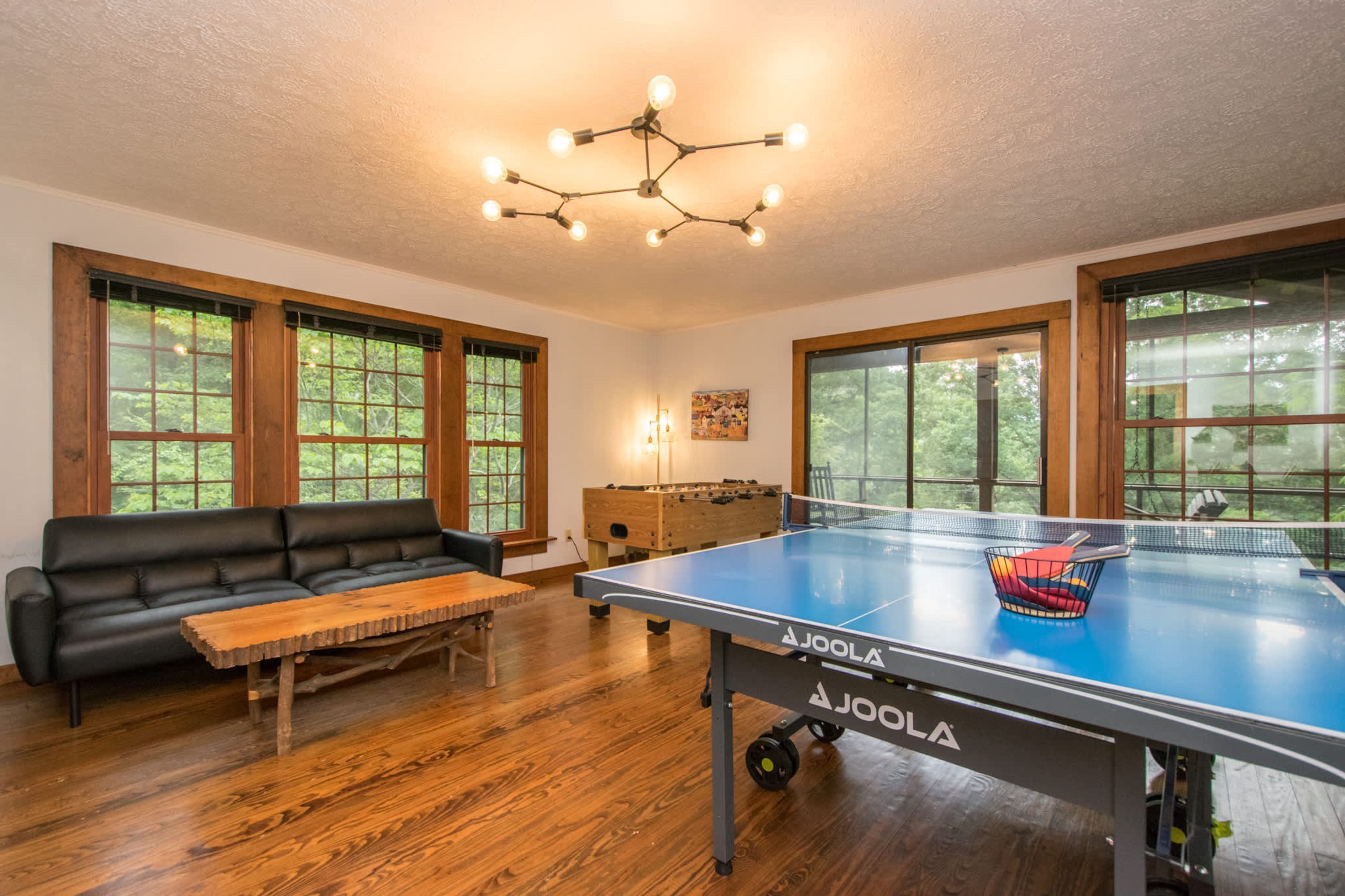 A room with a ping pong table, a sofa, and a wooden coffee table.