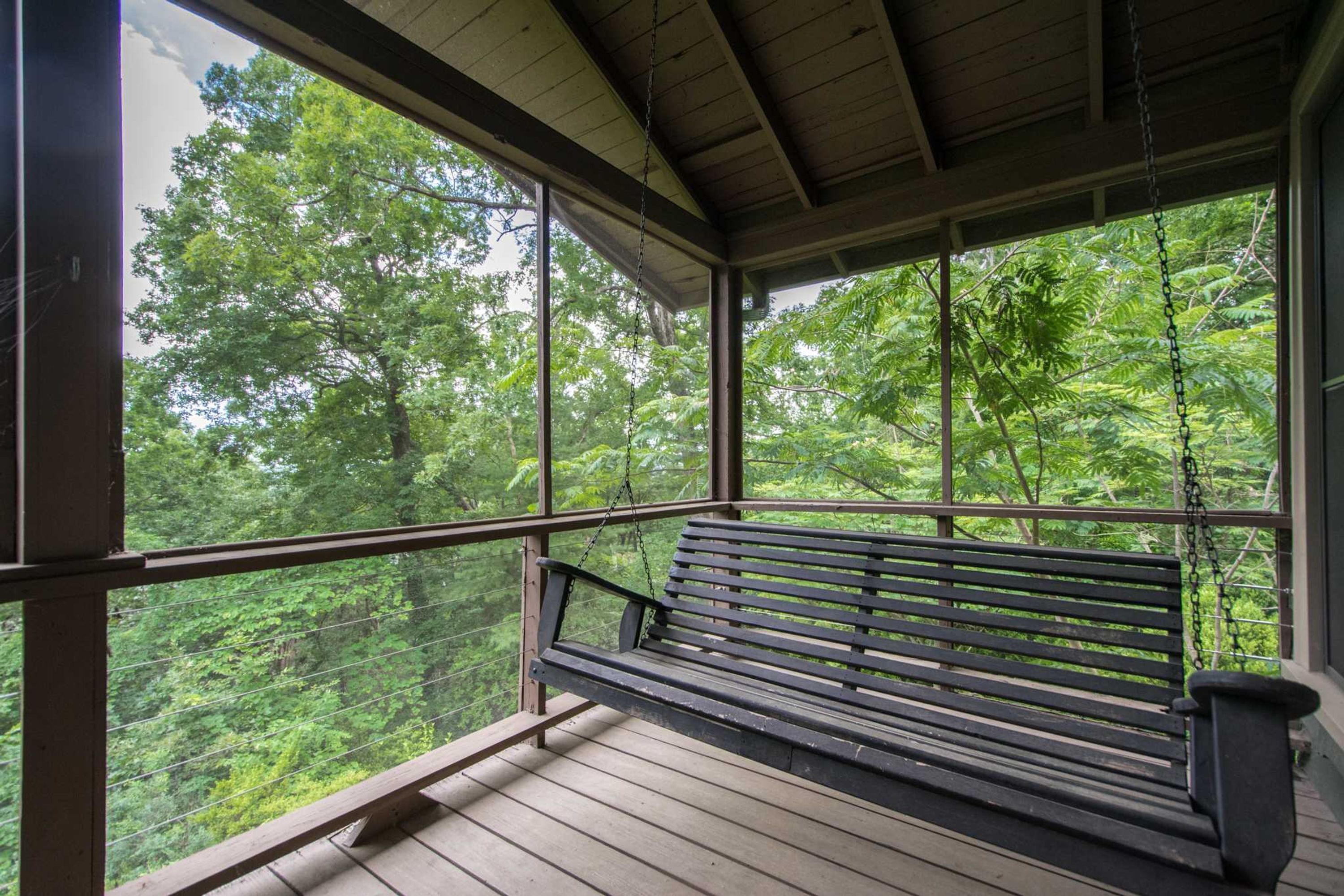 A wooden deck with a bench overlooking a forested area.