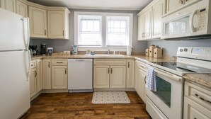 A kitchen with white cabinets, a dishwasher, a stove, and a microwave. - Cozy 3BR w Free Attraction Tix 6 Mins to Town (East Flat Rock)