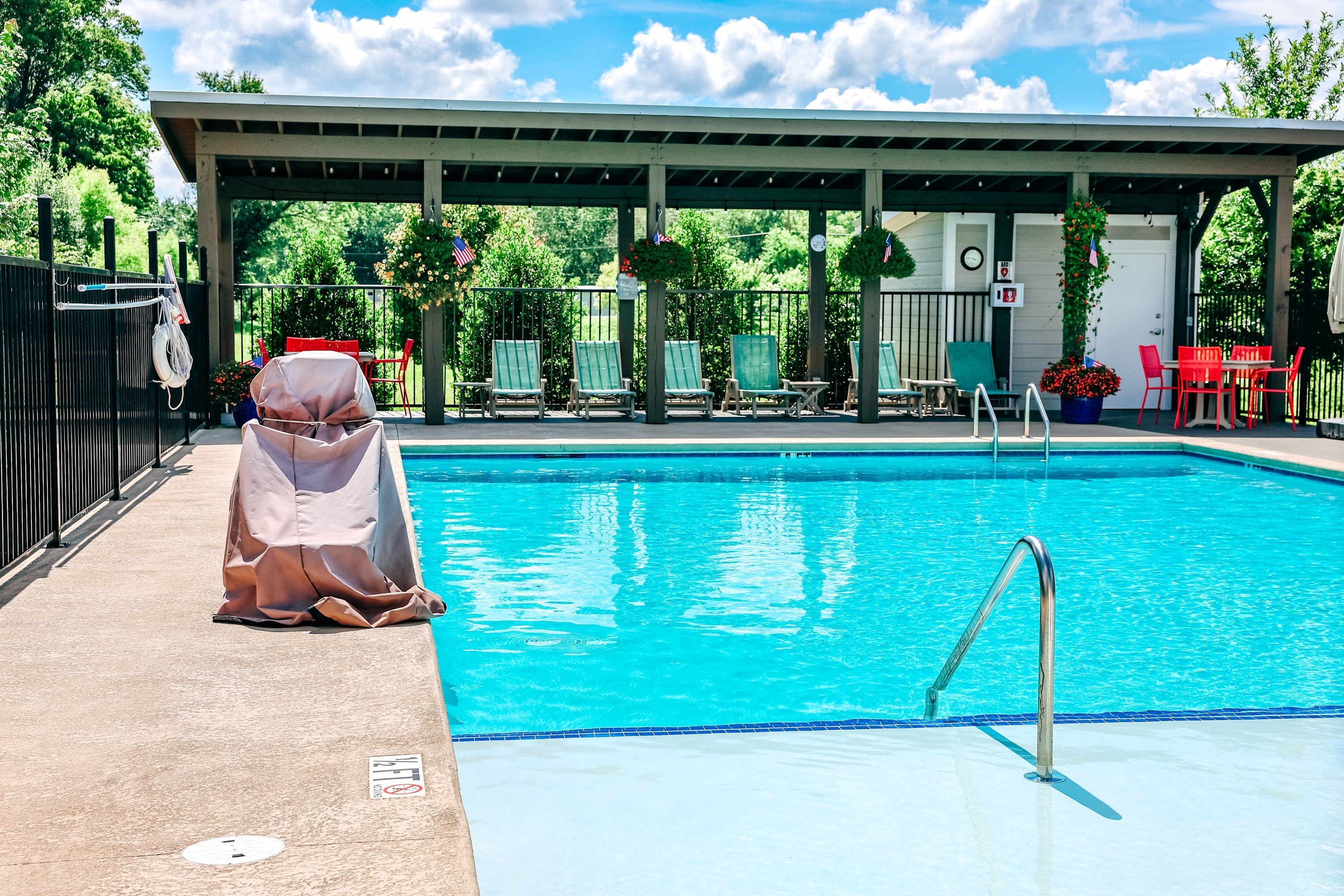 A swimming pool with lounge chairs and a covered seating area.