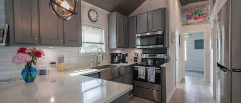 Una cocina moderna con armarios grises, electrodomésticos de acero inoxidable, una isla grande y un florero decorativo con flores.