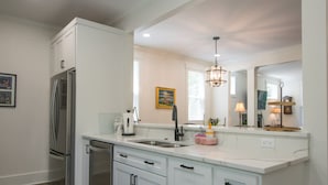 A modern kitchen with white cabinetry, stainless steel appliances, and a marble countertop. - Charming 3BR w Balconies Walk to Flat Rock Playhouse (Flat Rock)