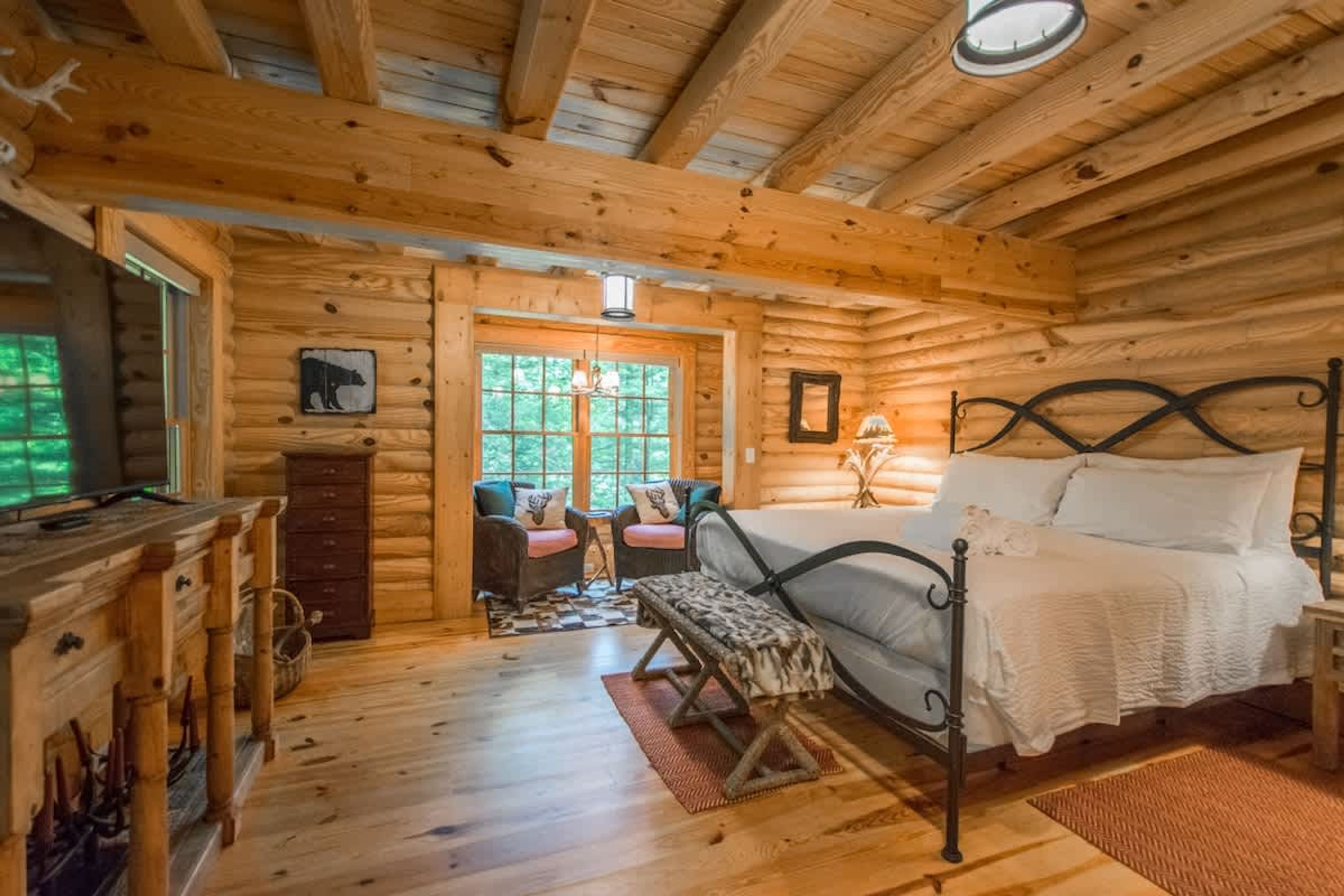 A log cabin bedroom with a bed, a dresser, a chair, and a desk.