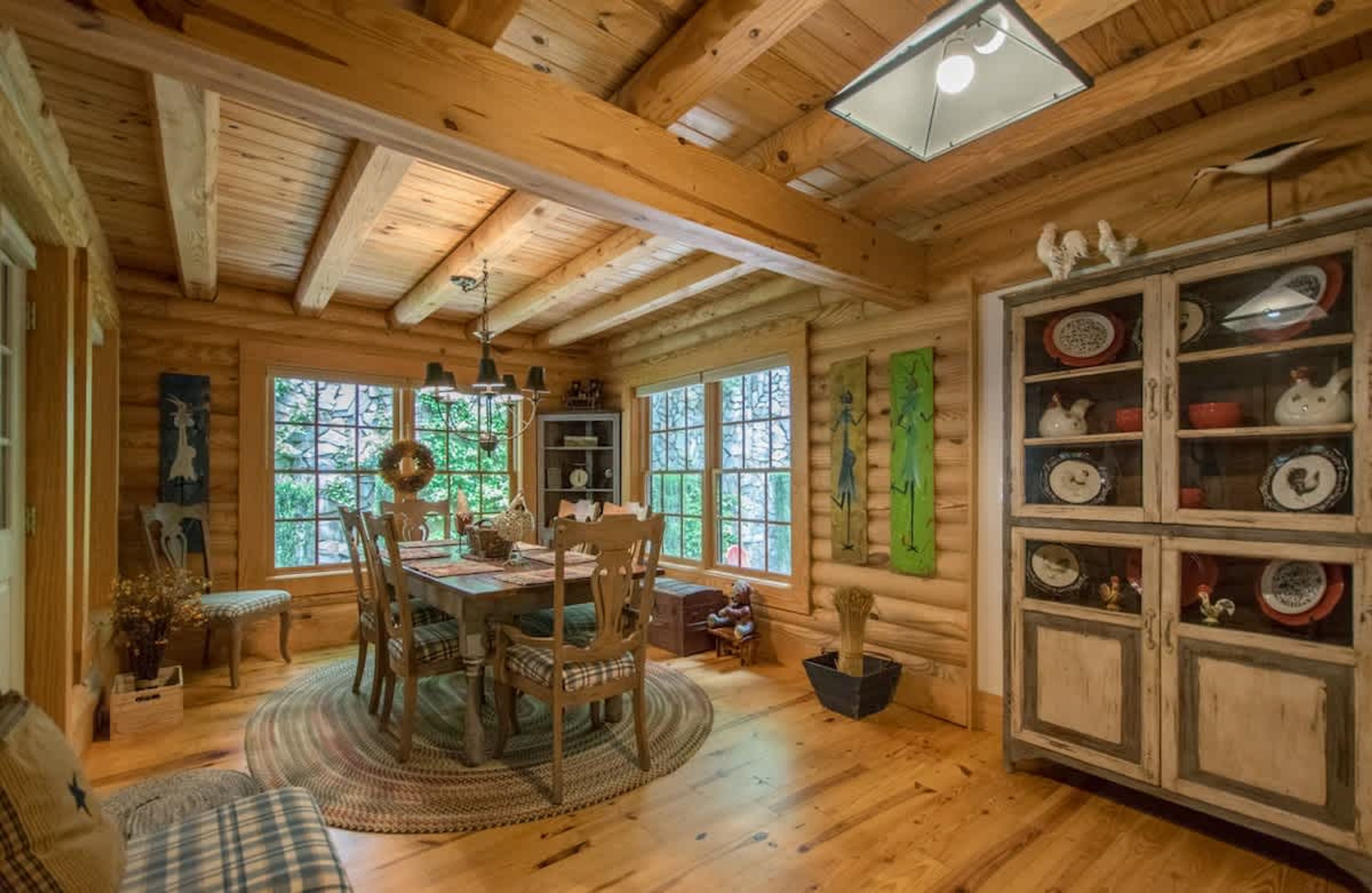 L’intérieur chaleureux d’un chalet avec une table à manger en bois, des chaises et un buffet contenant de la vaisselle.