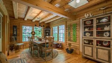 L’intérieur chaleureux d’un chalet avec une table à manger en bois, des chaises et un buffet contenant de la vaisselle.