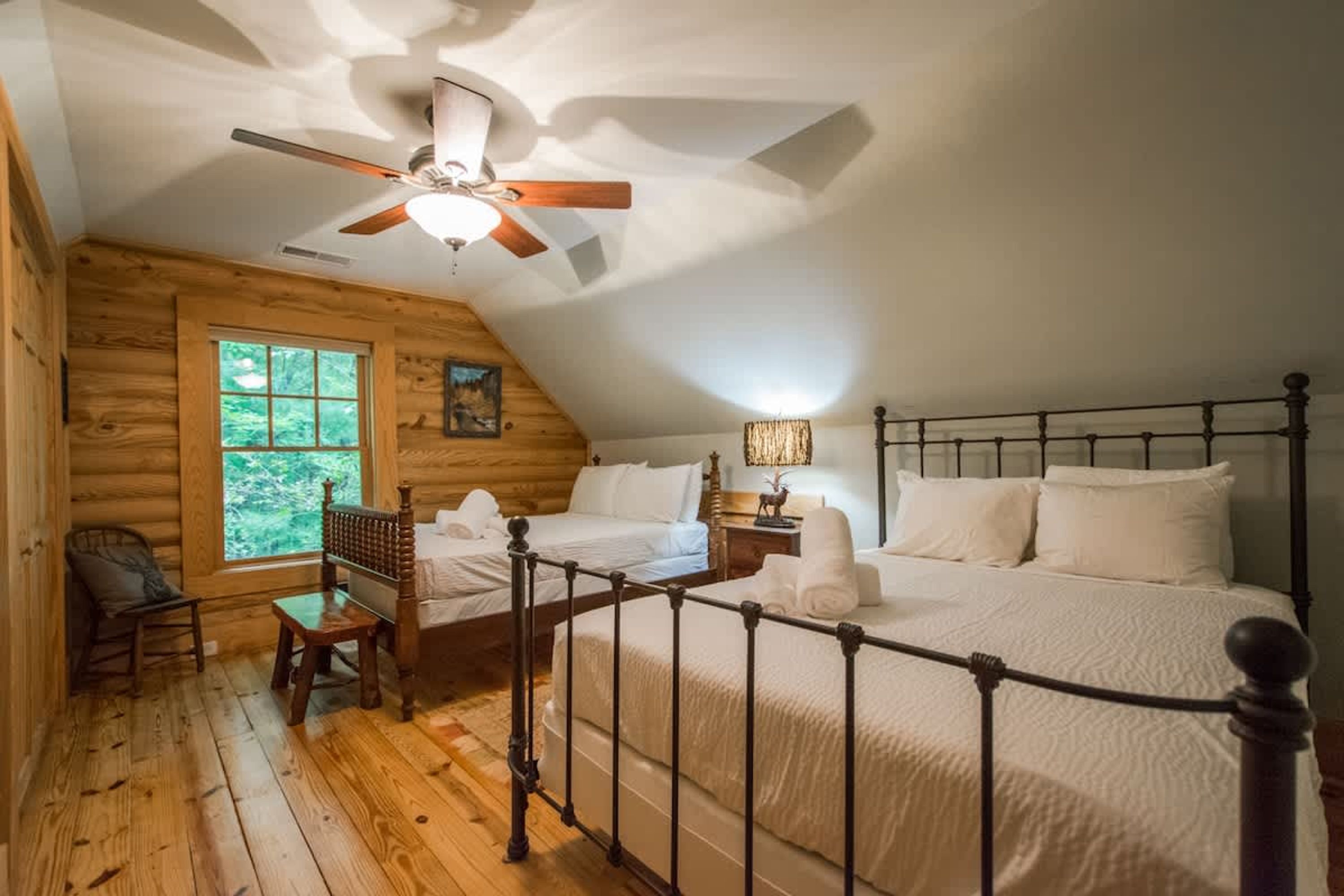 Ein gemütliches Schlafzimmer in einer Blockhütte mit einem Bett, einem Sessel, einem Nachttisch und einem Fenster.