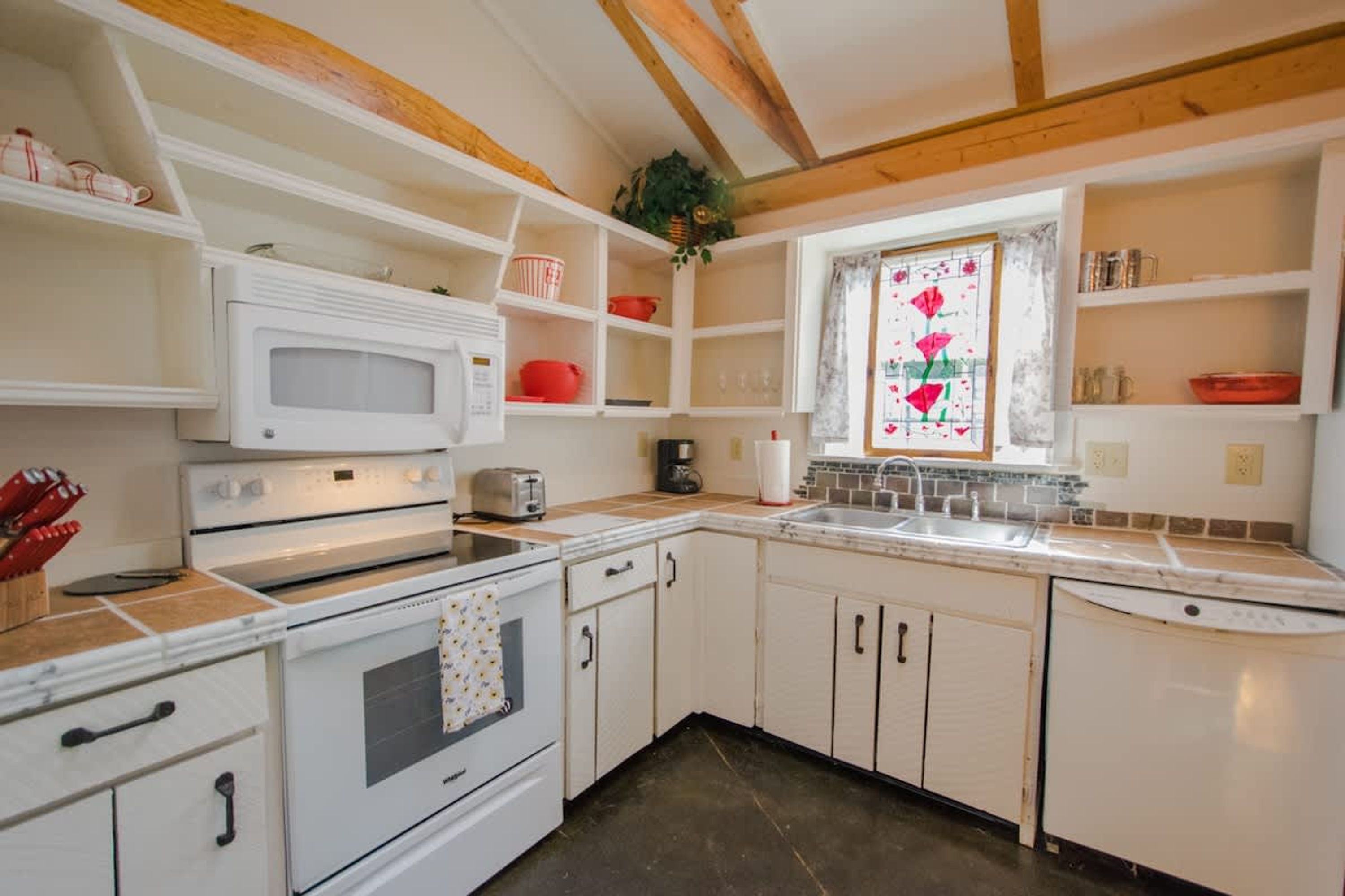 A kitchen with white cabinets, a microwave, a stove, and a sink.