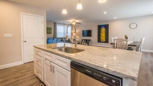 A modern kitchen with granite countertops, stainless steel appliances, and pendant lighting. - Art-inspired Retreat Free Daily Perks (Asheville)
