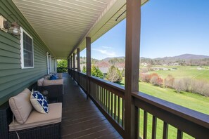 Une véranda aménagée avec des meubles en osier et offrant une vue sur un paysage verdoyant.